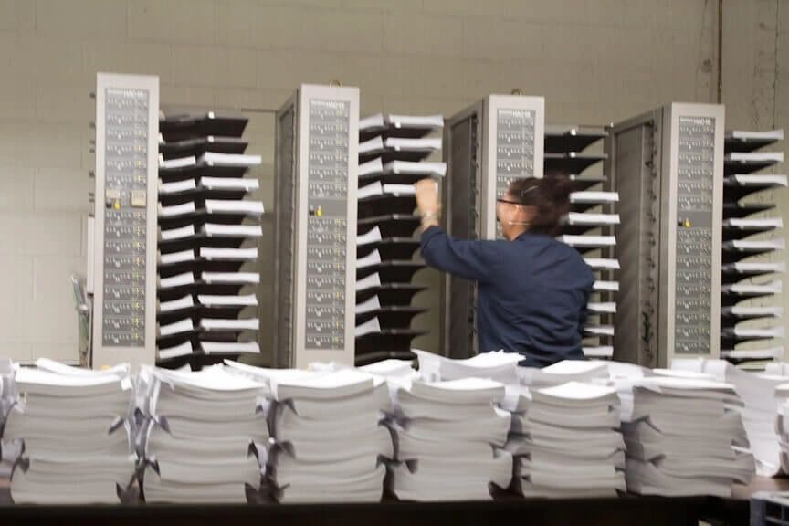 A man working in front of stacks of papers.