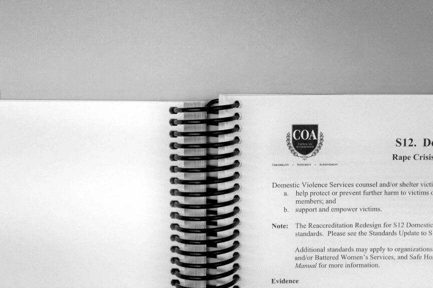 A spiral notebook with the coa logo on it.