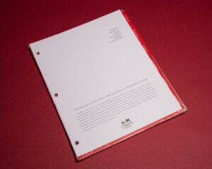 A red and white paper with three holes on it.